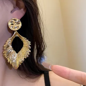 Close-up of golden hammered metal leaf pendant earring showing texture and shine