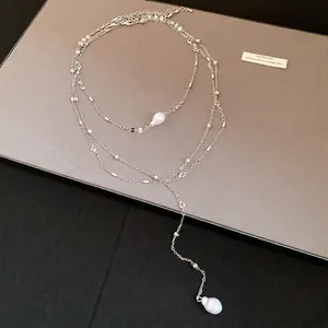 Elegant multi-layered silver necklace featuring teardrop pearls and clear stones.