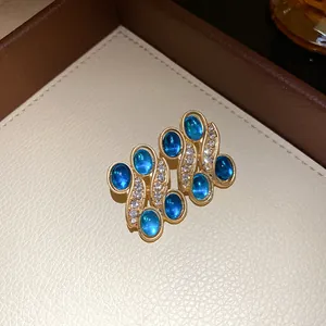 Close-up of vintage-inspired oval earrings with blue resin and sparkling rhinestones