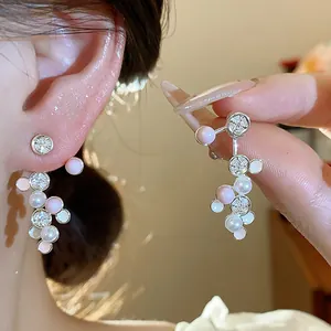 Detaillierte Nahaufnahme von silbernen Zirkonia-Ohrringen mit Emaille und Perlen.