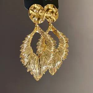 Close-up of gold metallic leaf earrings showing exquisite textured folds and elegant sheen.