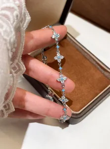 Macro detail of a refined silver bracelet featuring zircon clovers and turquoise accents