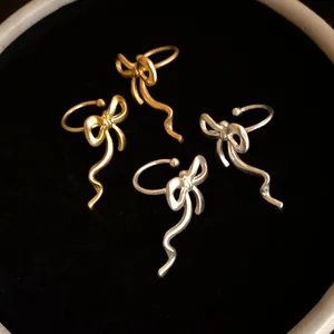 Detailed macro view of elegant gold and silver bow-shaped ribbon ear cuffs on black velvet