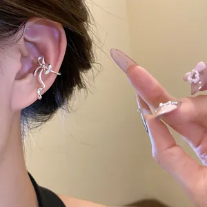 Detailed close-up of a stylish silver bow-shaped ear cuff worn on a model's ear