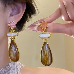 Close-up detail of vintage style gold earrings with pink and brown marbled resin dangles