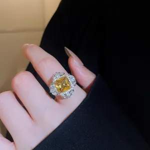 Close-up of a luxury square yellow zircon ring with elegant floral halo setting on finger