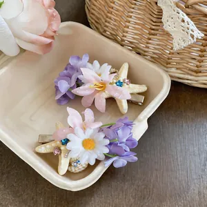 Detailed macro view of fabric flower and starfish hair clips with pearl and rhinestone accents.