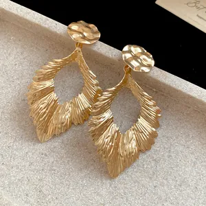 Detailed macro view of gold pleated leaf dangle earrings showing metallic texture and shine
