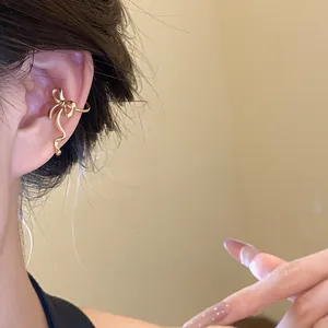 Detailed view of an elegant gold bowknot ear cuff worn on upper ear cartilage.