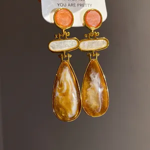 Macro detail view of vintage resin teardrop earrings with amber swirls and gold plating