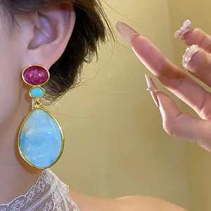 Elegant vintage resin drop earrings with marble blue teardrop pendant on model's ear