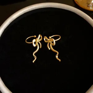 Close-up of elegant gold bow-knot ear cuffs for non-pierced ears on black velvet