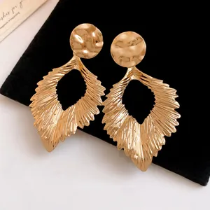 Detailed view of large gold-tone pleated leaf drop earrings with a metallic finish