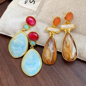Close-up of blue and amber marbled resin drop earrings with vintage gold frames