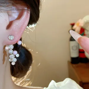 Detailansicht von Perlen- und Zirkonia-Ohrringen mit rosa Emaille-Details am Frauenohr