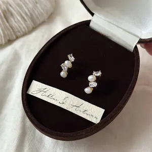 Elegant French style oval pearl and zircon stud earrings in a brown velvet jewelry box