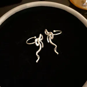 Close-up detail of elegant silver ribbon bow-knot ear cuffs on a plush black velvet base