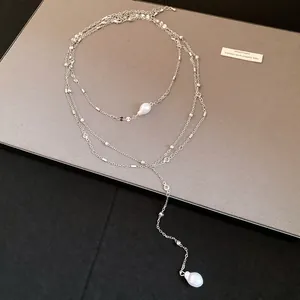 Close-up of a multi-layer silver-tone necklace with baroque pearls and clear stones