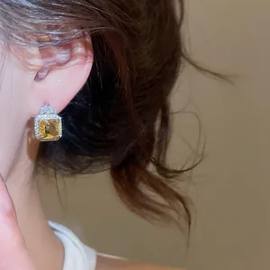 Close-up view of luxurious square yellow zircon earrings with a sparkling halo design.