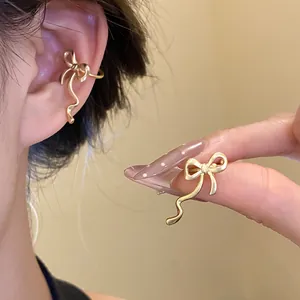 Close-up of elegant gold bow-shaped ear cuffs with a matte finish for non-pierced ears.
