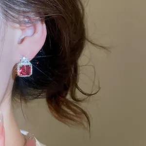 Detail view of a luxury square red zircon earring with sparkling halo effect