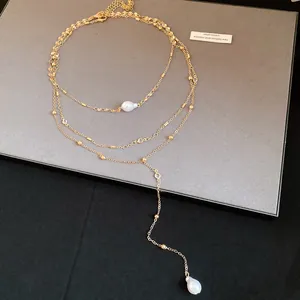 Detailed shot of a layered gold necklace featuring elegant baroque pearl pendants.