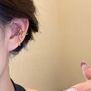 Close-up of elegant golden bow-shaped ear cuff worn on the ear without piercing