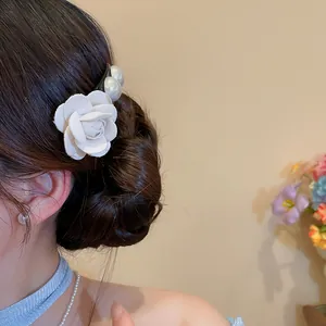 Detail view of a French style white fabric flower hair pin with pearls on a bun