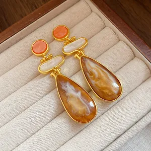 Close-up of vintage resin water drop earrings with golden finish and marble texture