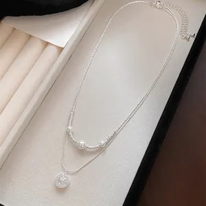 Detail of double-layered necklace with pearls and zircon North Star pendant in a tray.