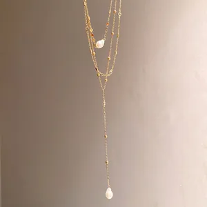 Close-up of gold multi-layer lariat necklace with elegant pearl pendants and crystal beads