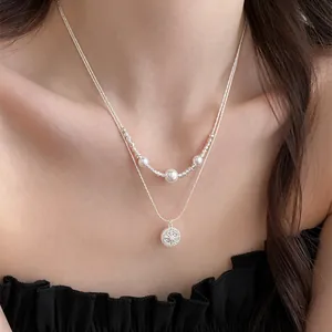 Close-up view of layered silver necklace with pearls and star sunburst pendant