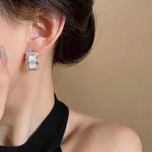 Close-up of elegant silver heart earring with white enamel and zircon detail