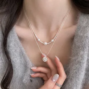 Close-up of layered necklace with pearls and zircon starburst pendant on model