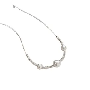 Elegant silver chain necklace with three minimalist white pearls on a white background