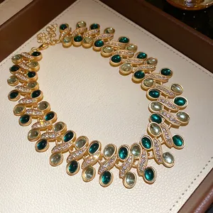 Detail view of vintage gold necklace with oval green stones and pavé rhinestones