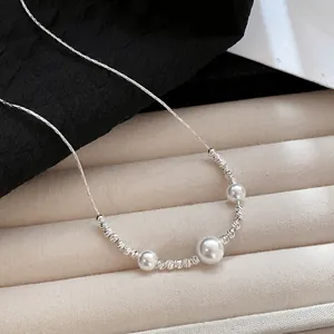 Close-up of elegant silver necklace with white pearls on a textured display tray