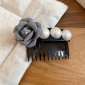 Detailed close-up of elegant hair comb featuring a grey fabric rose and three lustrous pearls
