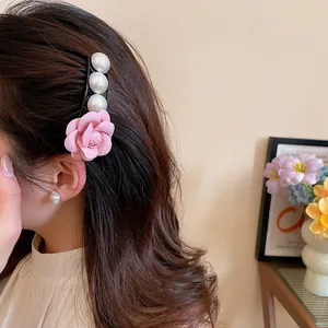 Close-up of a French style hair clip with a pink fabric rose and elegant pearls.