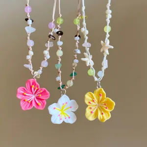 Detail of three dopamine beaded necklaces with pink white yellow flower pendants