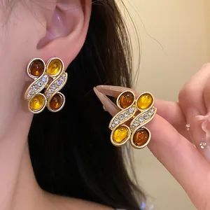 Macro detail of vintage gold-toned earrings featuring amber resin and rhinestones