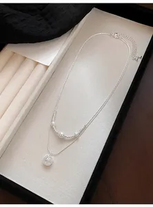 Detail of double-layer necklace with pearls and a sparkling zircon star pendant.