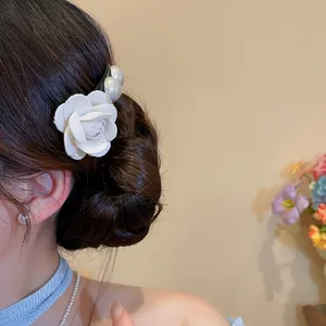 Detailed view of a French fabric camellia flower and pearl hair fork on an elegant bun.