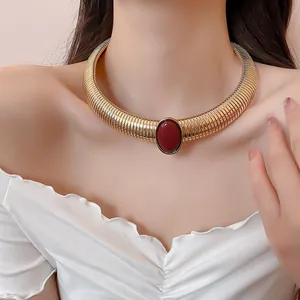 Détail du ras-du-cou serpentin doré avec pendentif ovale en résine rouge vintage.