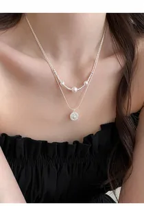 Close-up detail of double-layered silver necklace with pearls and starburst pendant