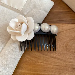 Detailed view of an elegant French-style fabric flower and pearl hair comb accessory.