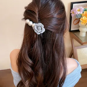 Detailed view of elegant fabric flower and pearl hair clip on brunette hair