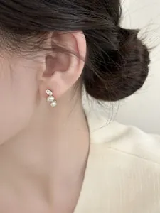 Detailed view of elegant French style stud earrings with pearls and oval zircon on ear