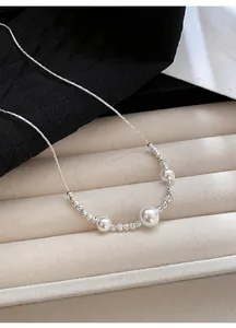 Detailed view of an elegant silver pearl necklace resting on a premium textured surface.