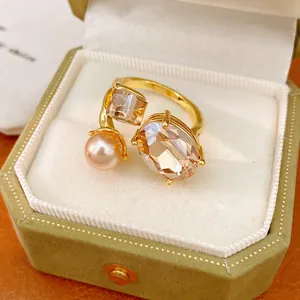 Detailed view of an open gold ring featuring oval and square gems with a pink pearl